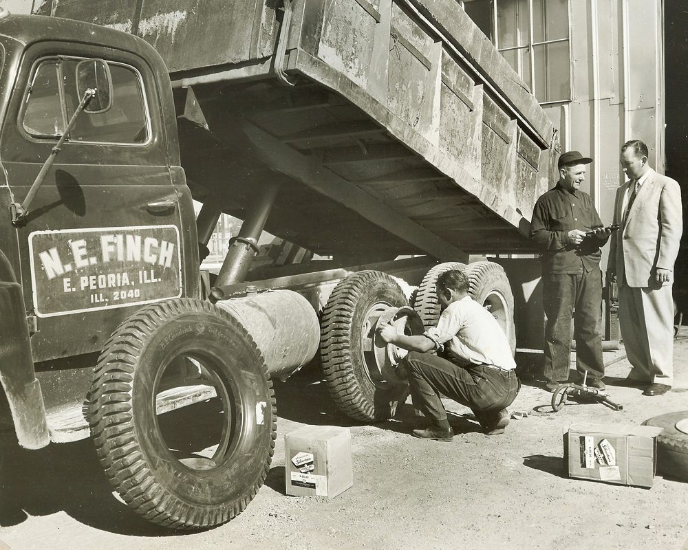 Peoria Metro | Black and white photo of man changing tires on an old dump truck